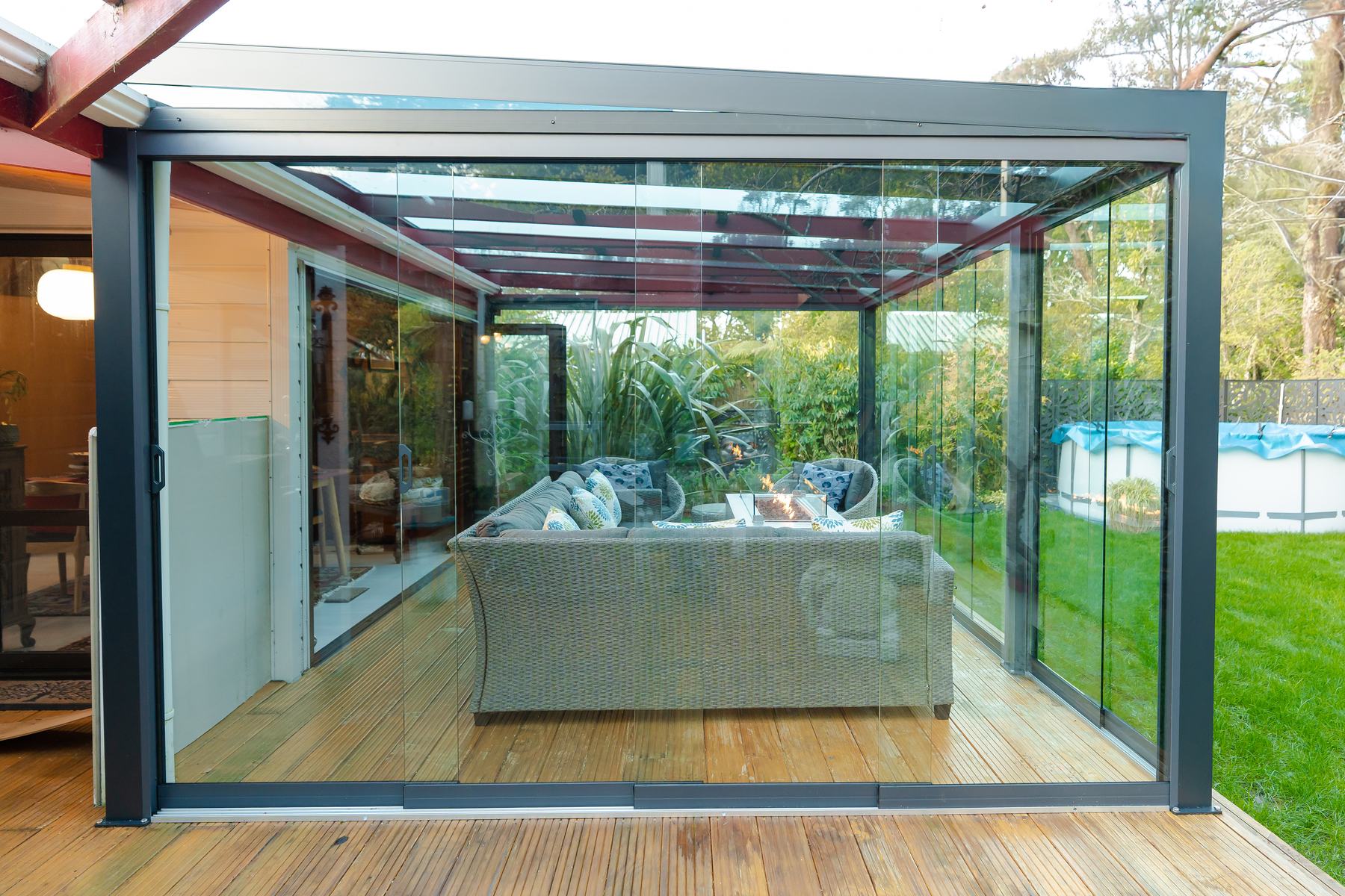 Glazed Elite Canopy room with a lounge and fire table, opening onto a garden